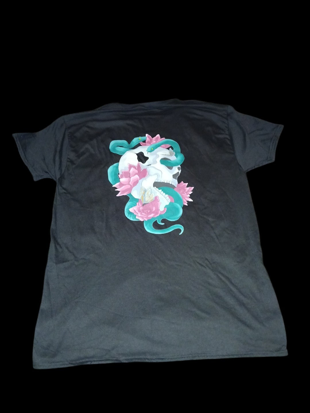 Venomous Volare black t-shirt featuring a back graphic of a skull, teal serpent, and pink lotus flowers.